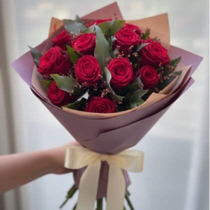 A stunning bride red rose bouquet held gracefully against a white wedding gown.