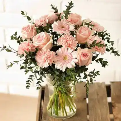 Handheld carnation and rose bridal bouquet featuring soft blush petals and elegant green foliage for a classic wedding look.