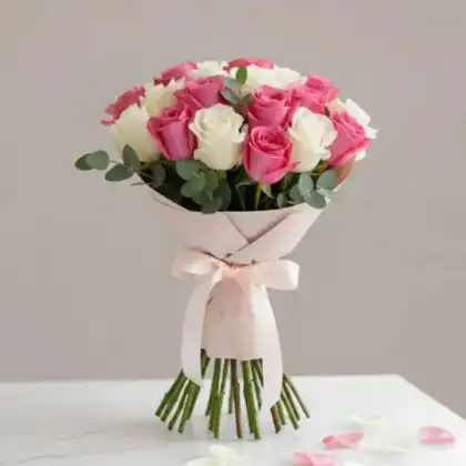 A hand-tied pink roses flower bouquet mixed with white blooms and lush green foliage against a soft background.