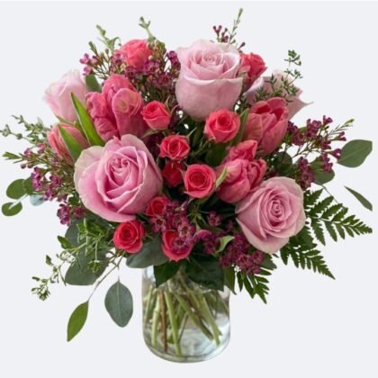 A beautiful Pink Roses and Tulips Bouquet arranged in a glass vase with lush greenery.