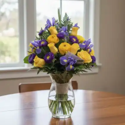 A vibrant rose and aster bouquet hand-tied with premium yellow roses and delicate purple petals in a sunbeam style.