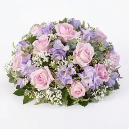 A handcrafted blush pink dried floral wreath featuring preserved roses and botanicals, perfect for rustic wall decoration.