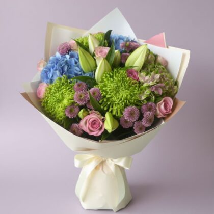 A beautifully hand-tied rose and hydrangea bouquet with lush green leaves in a soft lighting setting.