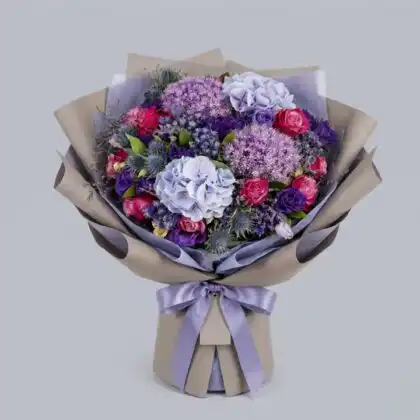 A vibrant carnation and hydrangea bouquet featuring deep velvet red blooms and soft purple petals in a decorative wrap.