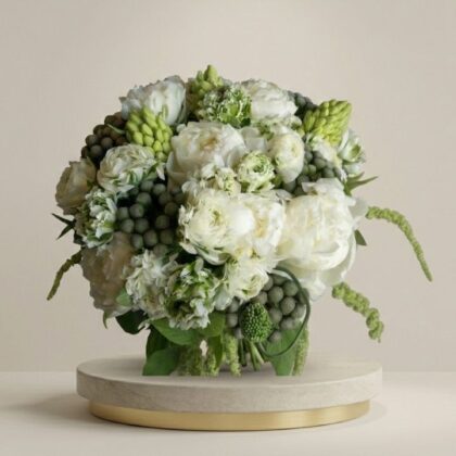Elegant white ranunculus and peonies bouquet arranged with green foliage in a luxury bridal style.