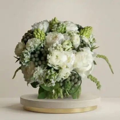 Elegant white ranunculus and peonies bouquet arranged with green foliage in a luxury bridal style.