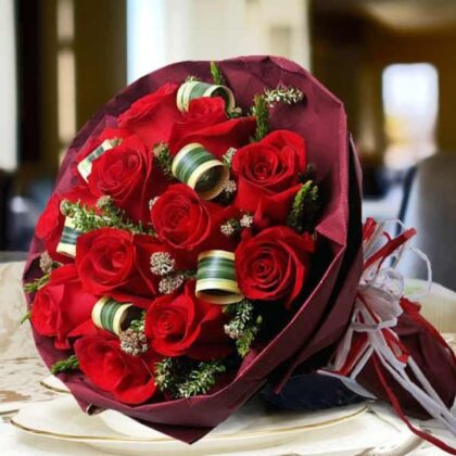 A beautifully arranged bouquet of vibrant red roses in a bouquet with elegant wrapping.