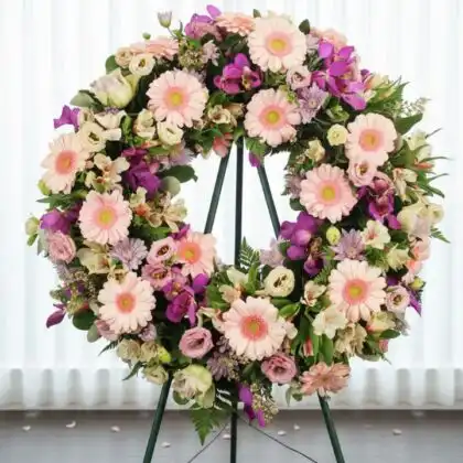Elegant orchid wreath on stand featuring a circular arrangement of soft pastel pink and purple blossoms.