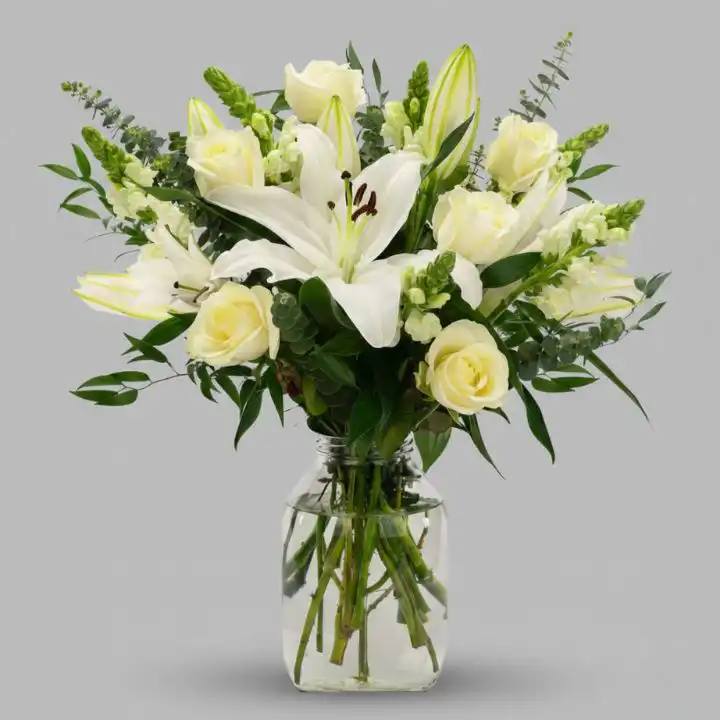 Pure Bliss White Lily & Rose Bouquet 1 A beautiful lily and white rose bouquet arranged with fresh greenery for an elegant look.