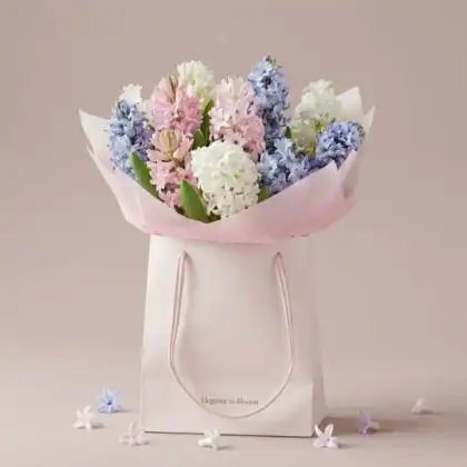 A beautifully arranged hyacinth flower bouquet featuring soft pastel purple and blue blooms wrapped in elegant paper.