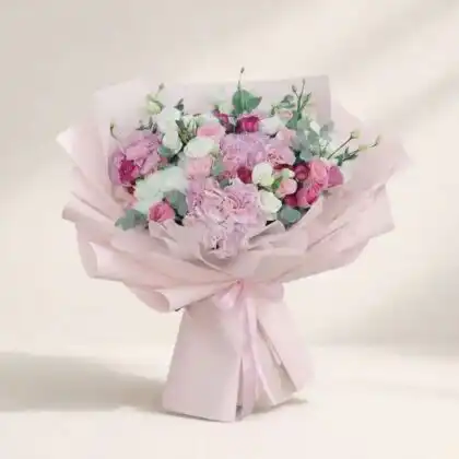 A lush pink hydrangea and rose bouquet arranged with green foliage in a sophisticated floral display.