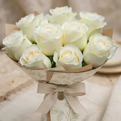 Hand-tied white silk rose bouquet with ten fresh roses and dark green leaves.