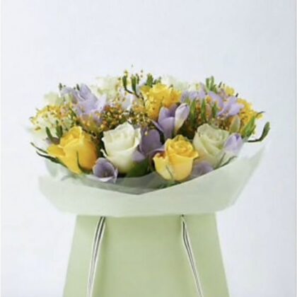 A hand-tied rose and freesia bouquet featuring soft pastel blooms and lush greenery in a decorative wrap.