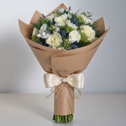 A stunning white rose and blue thistle bouquet arranged with green foliage for a rustic wedding theme.