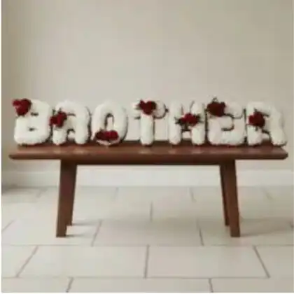 A serene Brother Letter Tribute made of fresh white carnations with blue floral accents for a funeral memorial