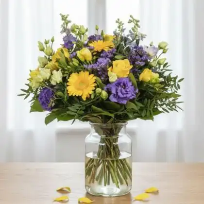 A vibrant carnation and roses flower bouquet professionally arranged with lush greenery and elegant ribbon detailing.