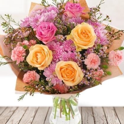A beautifully arranged chrysanthemum and roses bouquet featuring soft pink petals and lush green foliage in a natural setting.