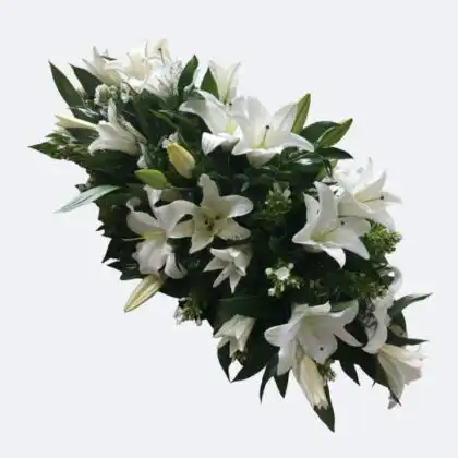 A large and elegant White Lily Casket Spray arranged with lush greenery for a funeral tribute.