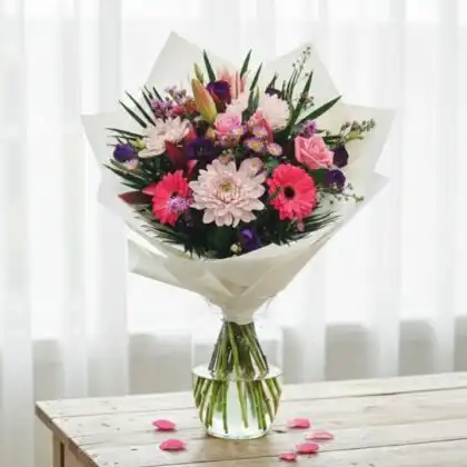 Close-up of a lush magenta flower bouquet blended with soft peach roses and greenery in a stylish arrangement.