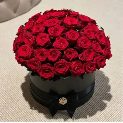 A luxury black hat box filled with 50 roses in a box creating a dense and elegant floral display.