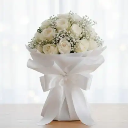 A stunning bridal white rose bouquet accented with delicate baby's breath flowers for a classic wedding look.