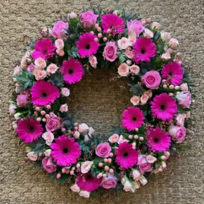 A circular memorial arrangement of pink gerbera flowers wreaths funerals services to honor loved ones.