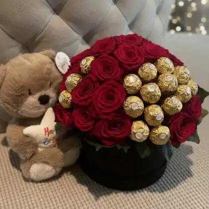 A luxury hatbox featuring vibrant red roses and Ferrero Rocher chocolates, creating a stunning red roses and ferrero bouquet with a plush keepsake.