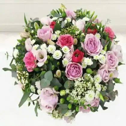 A small posy for funeral featuring soft pink roses and white lilies accented with lush green foliage.