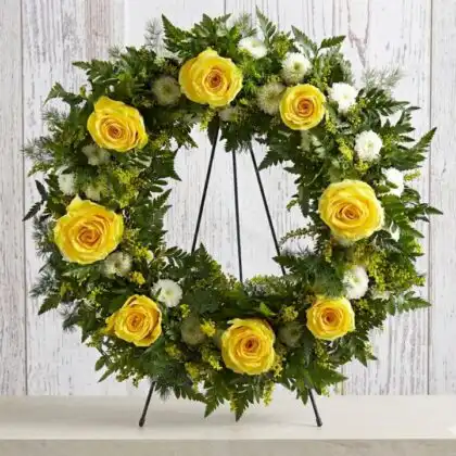 A circular arrangement of fresh flower funeral wreaths featuring vibrant yellow roses and white lilies on a clean background.