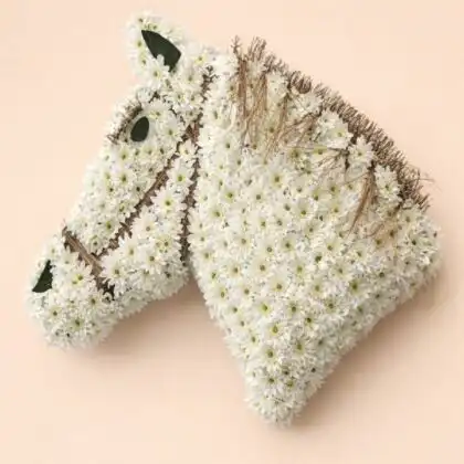 A detailed horse head funeral flowers arrangement made of white carnations and greenery for a memorial service.