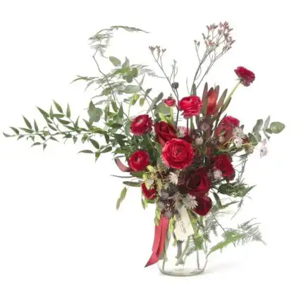 Handcrafted Red Roses and Ranunculus bouquet in a glass vase with wild ferns and eucalyptus foliage.
