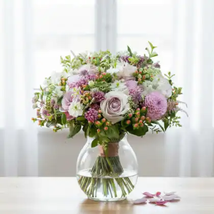 A vibrant Dahlia and Rose Bouquet featuring soft pink petals and lush greenery arranged in a decorative style.