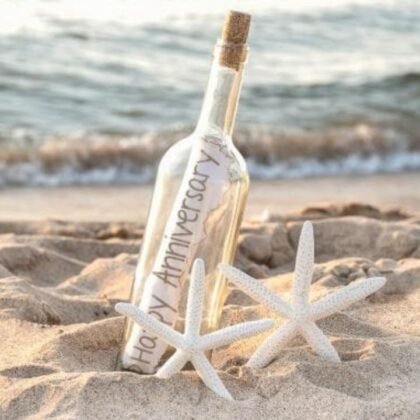 A Marriage Anniversary Greeting Card rolled inside a glass bottle on a sandy beach with two white starfishes.