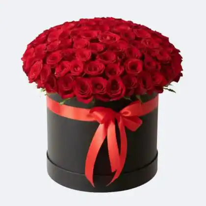A luxurious display of deep red rose arrangements carefully gathered inside a sophisticated midnight black velvet hatbox.