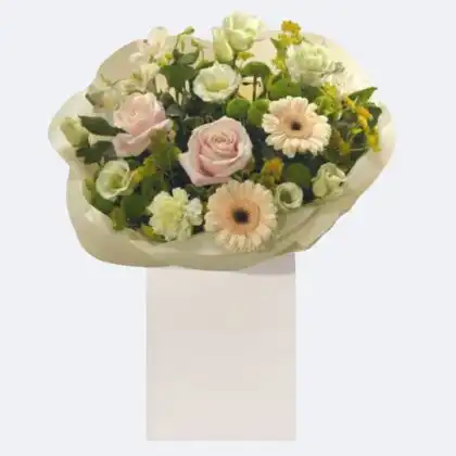 A beautiful flowers gift bag containing fresh pink roses, white lilies, and pastel gerberas arranged with green foliage.