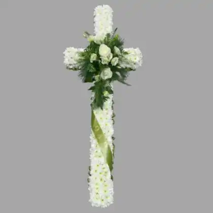 An elegant arrangement of white roses and lilies shaped as floral crosses for funerals placed on a wooden easel.