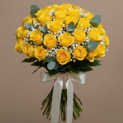 A round bridal bouquet featuring 50 yellow roses delivery with white baby's breath and fresh green eucalyptus leaves.