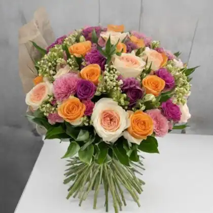Vibrant english garden rose bouquet featuring sunset orange, deep purple, and peach blossoms with lush greenery.