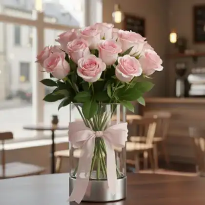A handcrafted light pink rose bouquet with fresh green leaves and white baby's breath flowers in a premium wrap.