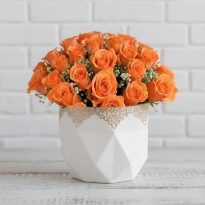 A vibrant Orange Rose Bouquet accented with white baby’s breath and green leaves against a clean white background.