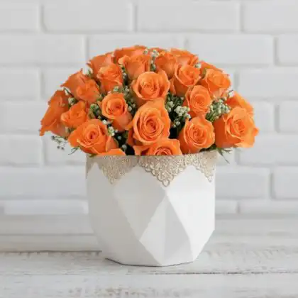 A vibrant Orange Rose Bouquet accented with white baby’s breath and green leaves against a clean white background.