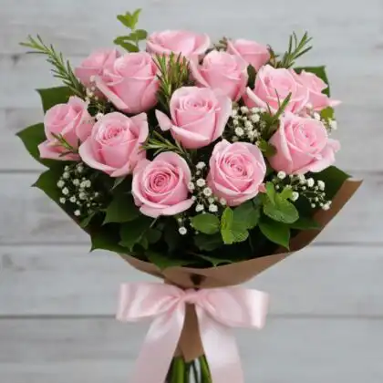A handcrafted flower bouquet pink roses accented with fresh rosemary, mint leaves, and white gypsophila in kraft paper.
