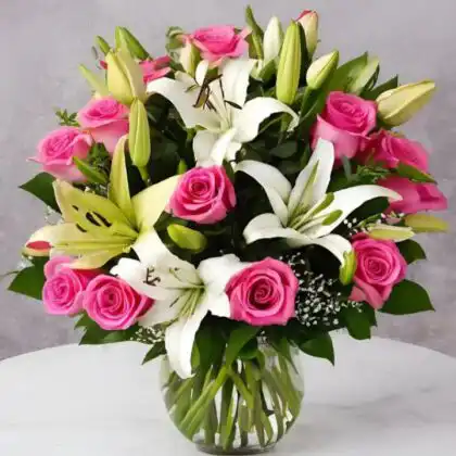 A hand-tied white lily and pink rose bouquet with lush green foliage in a sophisticated arrangement.
