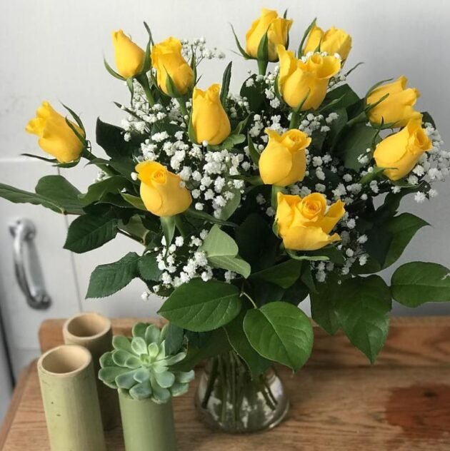 12 Yellow Rose Mother's Day flower bouquet delivery in a man's hand, an elegant and thoughtful gift.