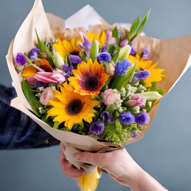 Spring Flowers for Mother's Day UK bouquet in a man's hand, featuring tulips, lilies, and daisies.