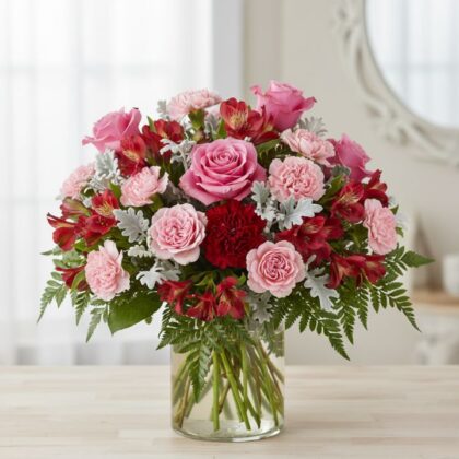 A vibrant alstroemeria and carnations bouquet accented with deep velvet roses arranged elegantly in a glass vase.