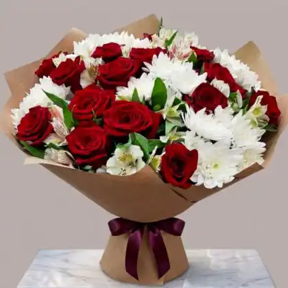Hand-tied chrysanthemum and roses flower arrangement with deep red roses and fluffy white blooms in a glass vase.