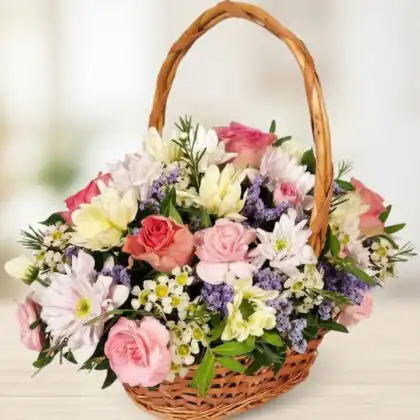 A handcrafted floral gift baskets featuring fresh pink roses and white chrysanthemums in a rustic wicker basket.