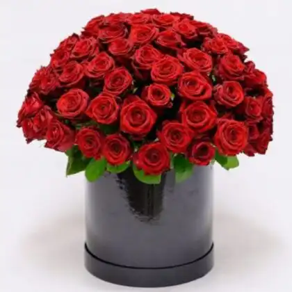 A luxury black hatbox filled with a dense arrangement of fresh red rose blooms against a white background.