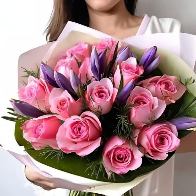 Pink roses and crocus Mothers day flowers bouquet held in a woman's hand, perfect for Mother's Day gifting.